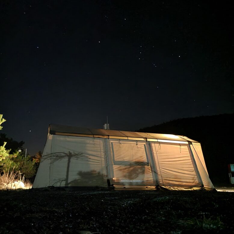 텐트 위로 별이 보이는 밤하늘의 사진