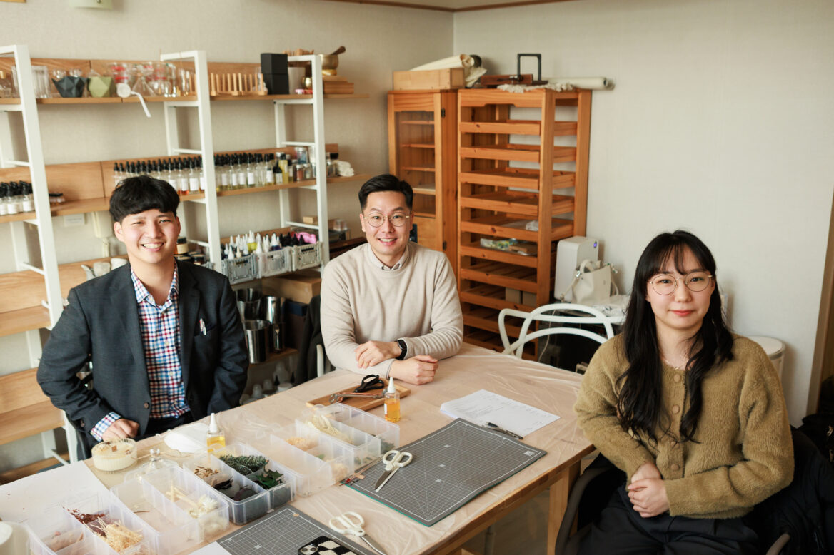 공방에서 김동진 대리, 이윤호 상담원 주임, 송유정 상담원 주임이 웃으며 정면을 보는 모습