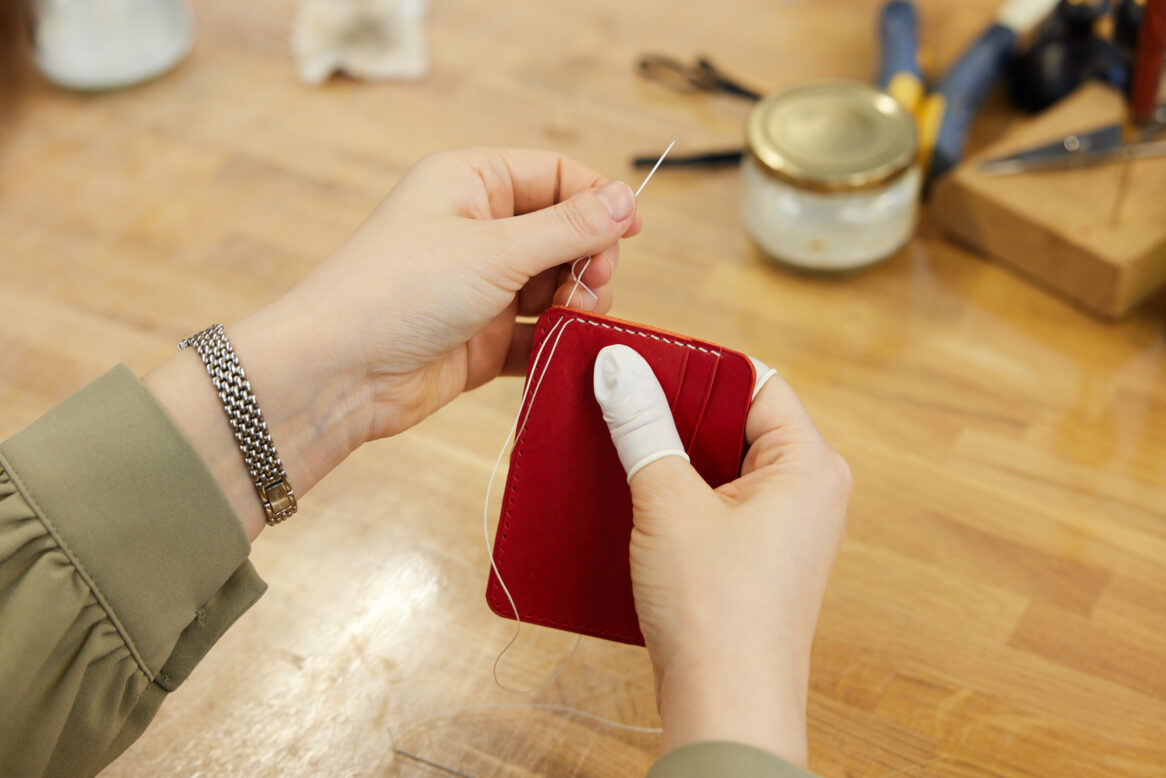 최희정 주임의 두 손이 한 땀 한 땀 구멍에 바늘을 교차하는 사진