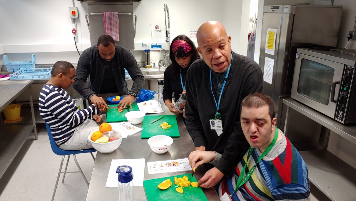 장애인직업훈련에서 다섯 명의 훈련생들이 요리과 수업을 듣고 있는 모습의 사진