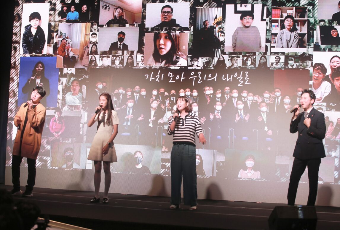 장애인고용촉진대회에서 네 명의 사람들이 마이크를 들고 축하 공연을 하고 있는 모습