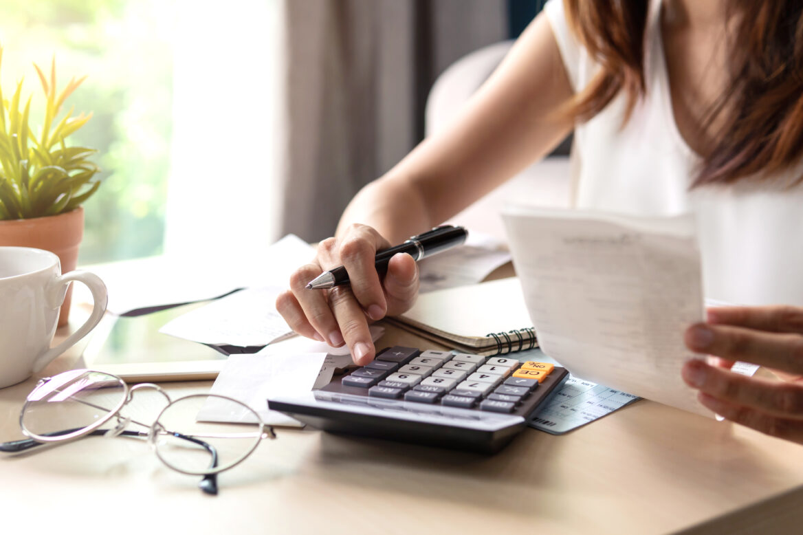 젊은 여성이 계산기로 지출비를 계산하고 있는 모습의 사진