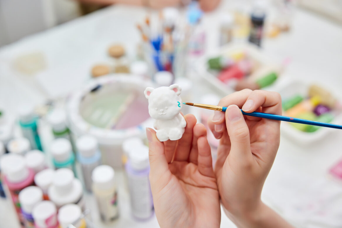 귀여운 캐릭터에 채색작업을 하고 있는 사진/ 왼손으로 캐릭터를 들고 오른 손으로 붓으로 색을 칠하고 있다.