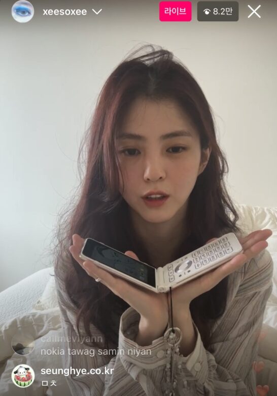 배우 한소희가 인스타그램 라이브방송에서 폴더폰 사용하는 모습을 보여주고 있는 장면