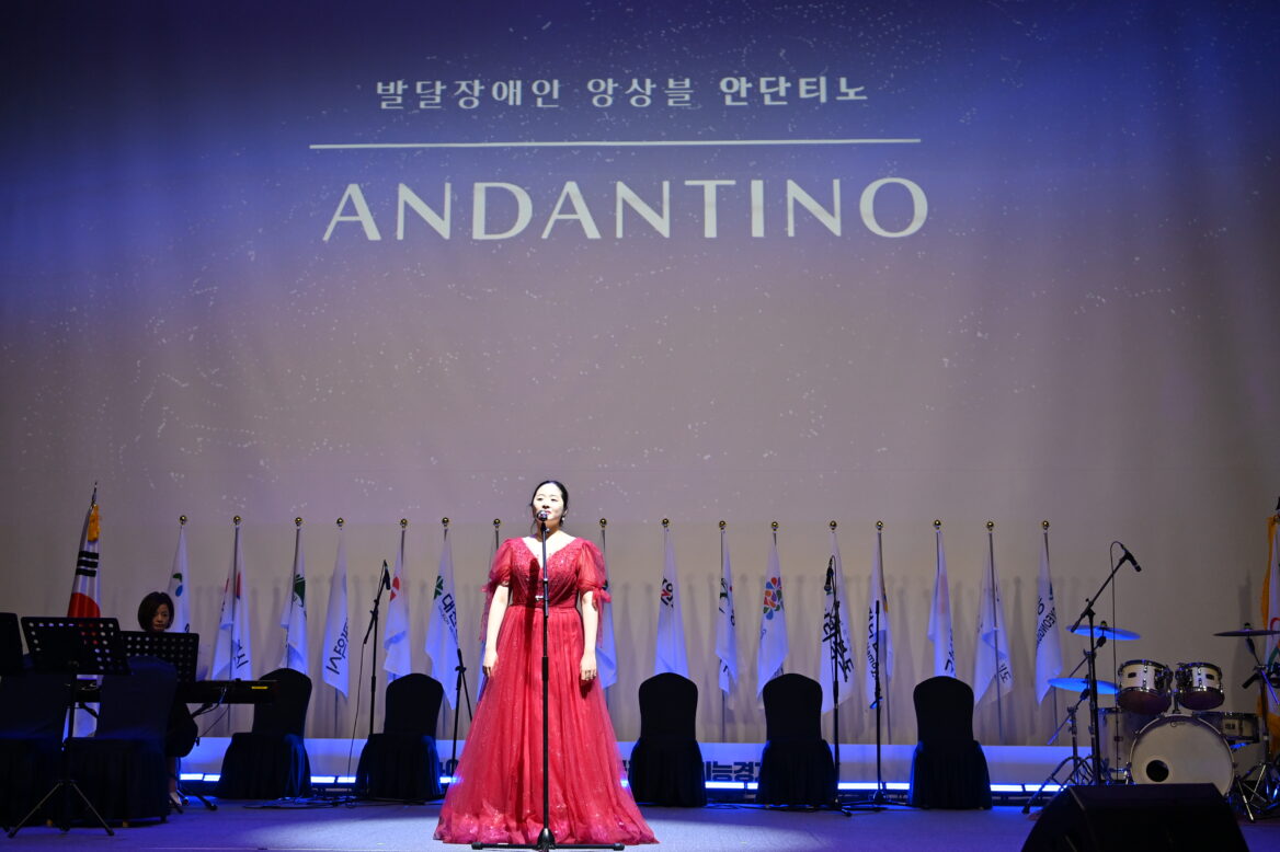 빨간 드레스를 입은 여성이 장애예술인 경주 공연에서 노래하고 있는 사진