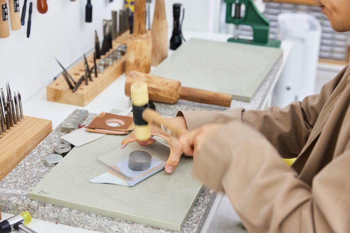 김혜석 대리가 가죽 위에 동그란 커터를 올리고 망치질 하는 모습